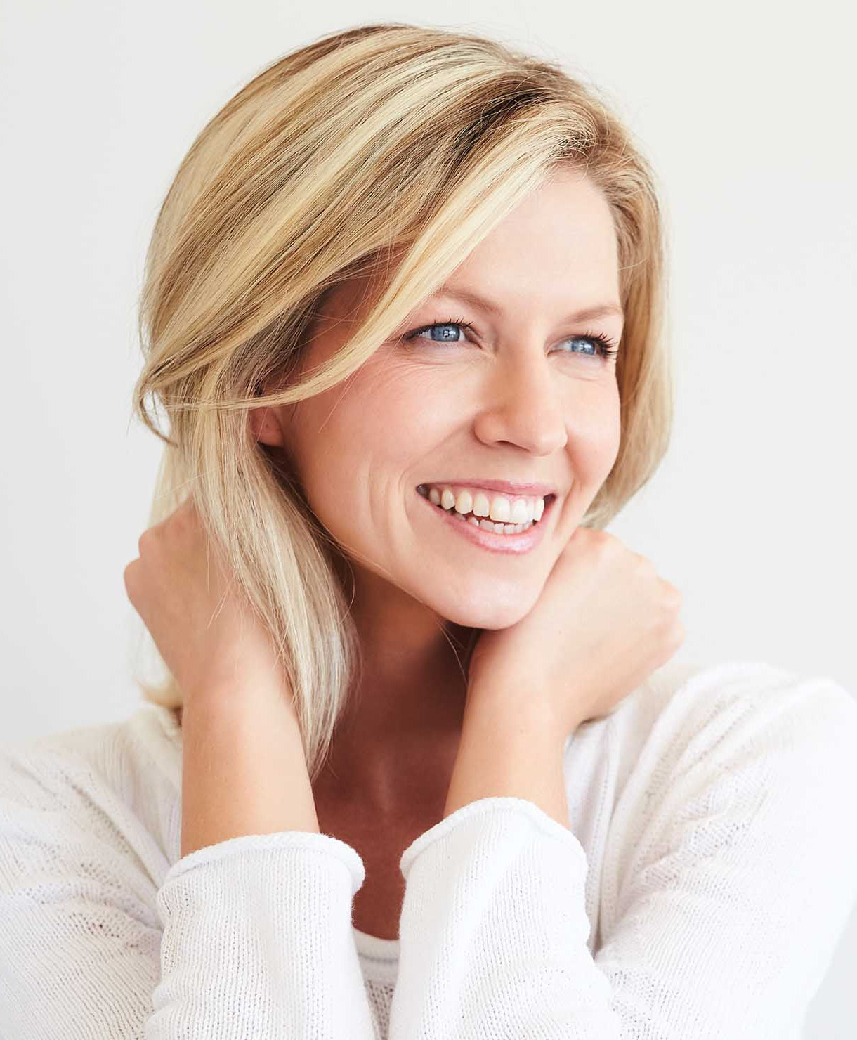 Woman with blonde hair smiling against a white background