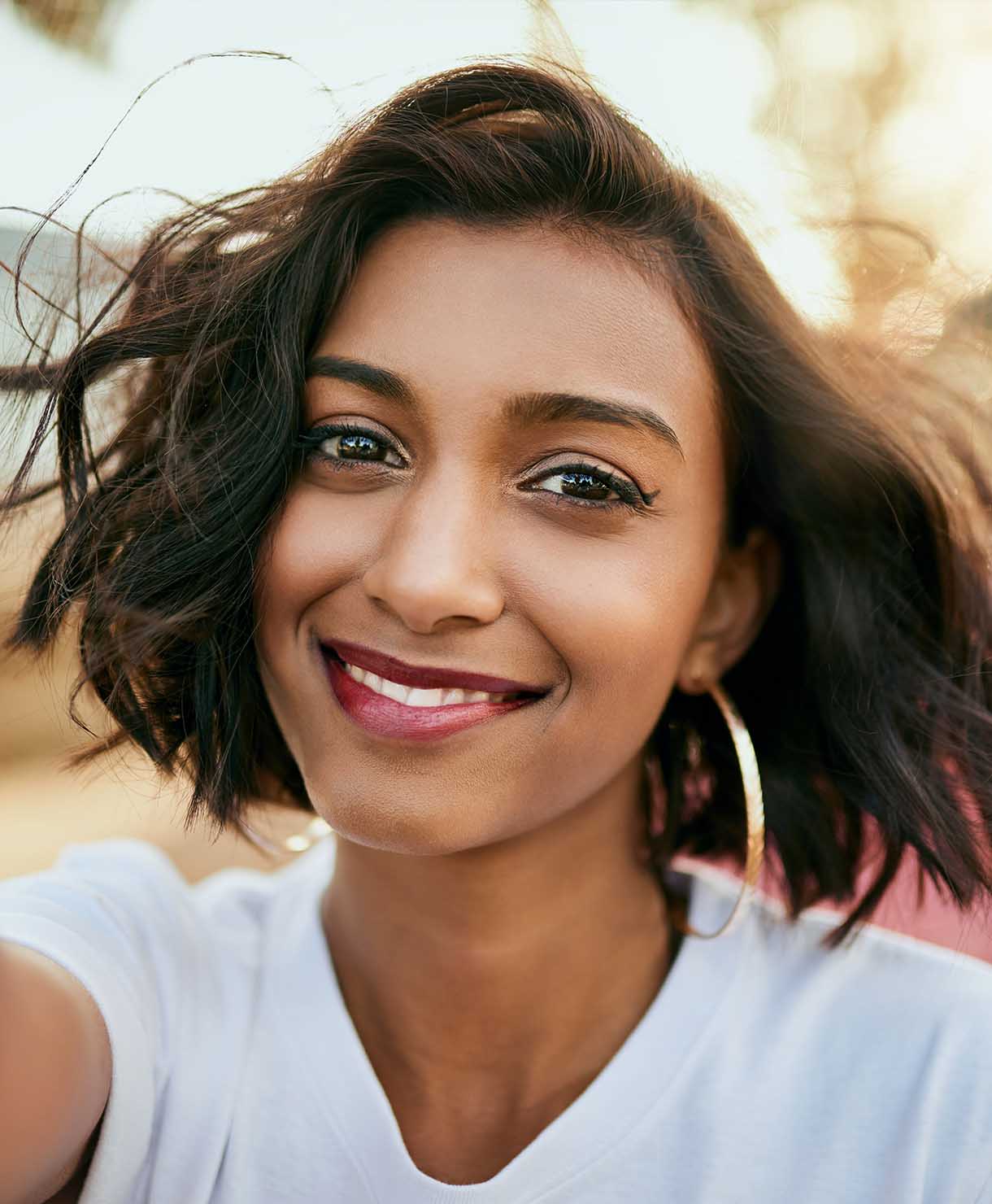 Woman with short dark hair smiling outdoors