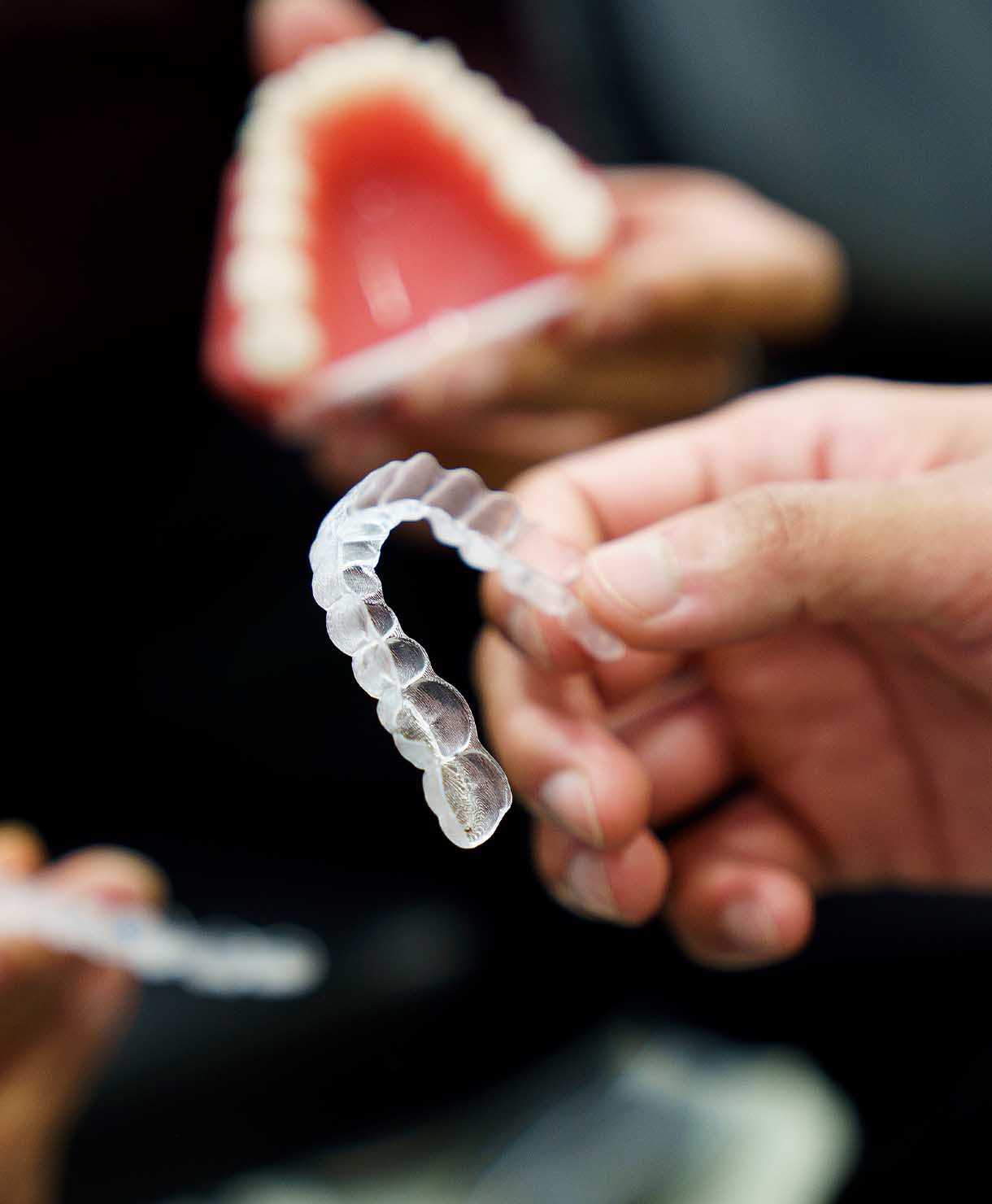 Clear dental aligner held by a person with a blurred background