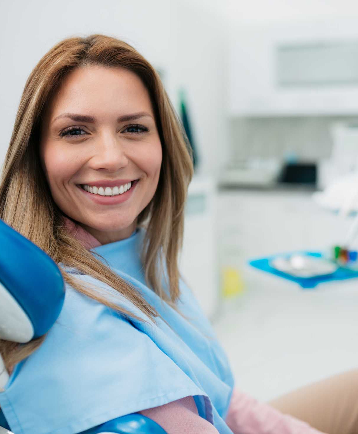 Woman sitting in a dental chair with a blurred dental office background