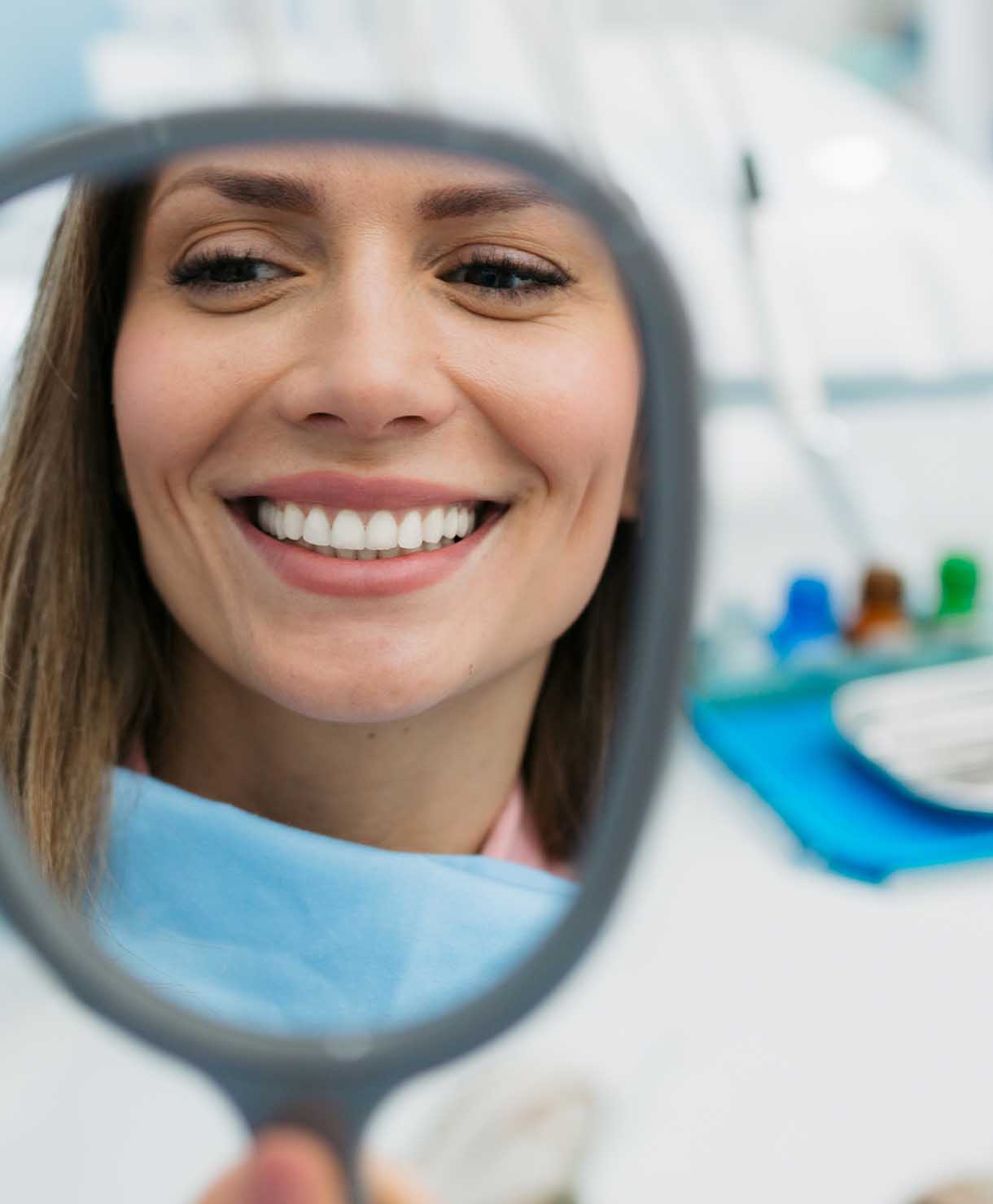 Woman smiling with a dental mirror reflecting her face