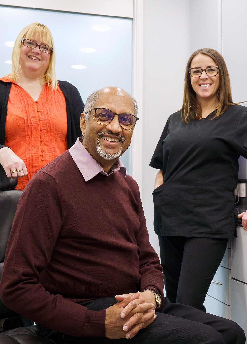 Man sitting with two women standing behind him in an office setting