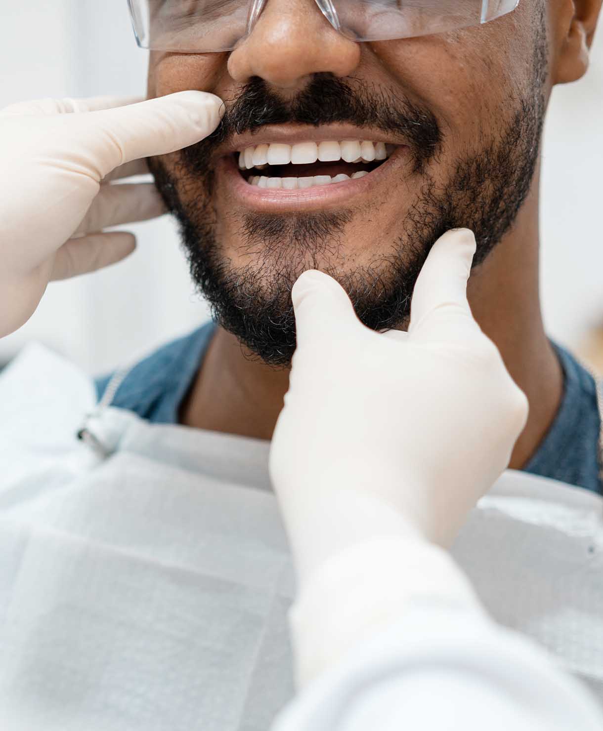 Person receiving dental check-up with gloved hands and dental tools