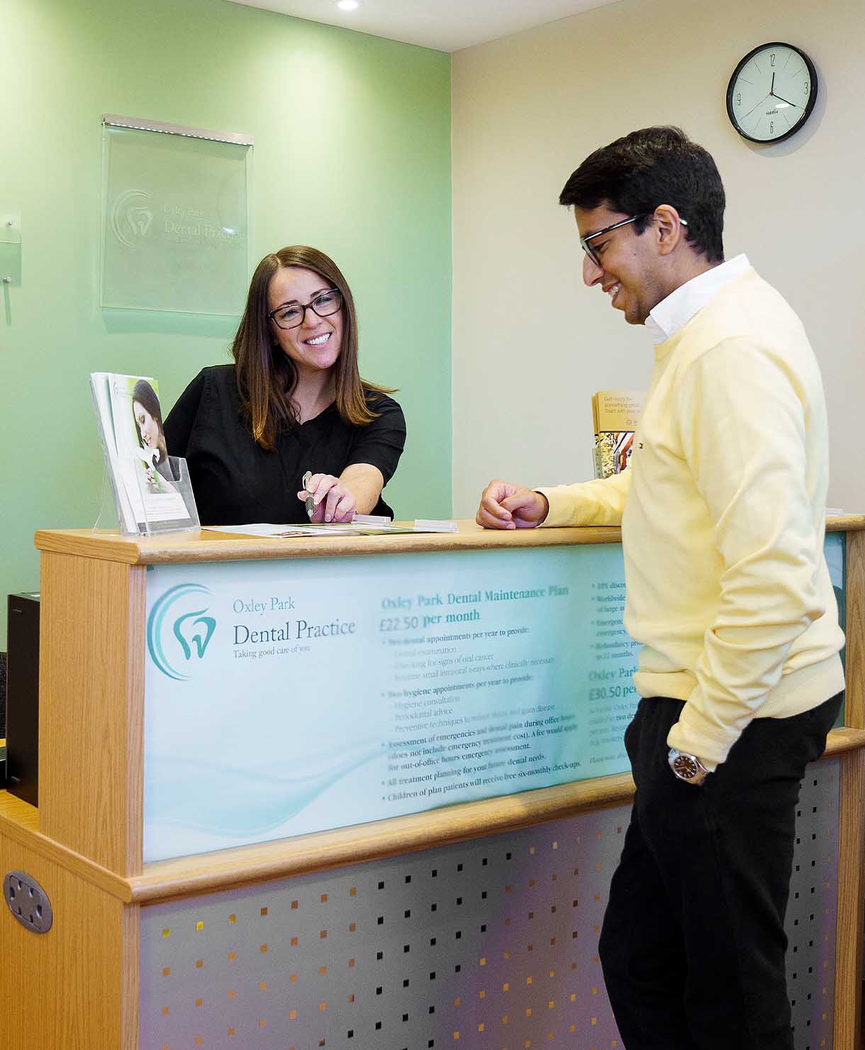 Person at a dental practice reception desk interacting with a staff member.