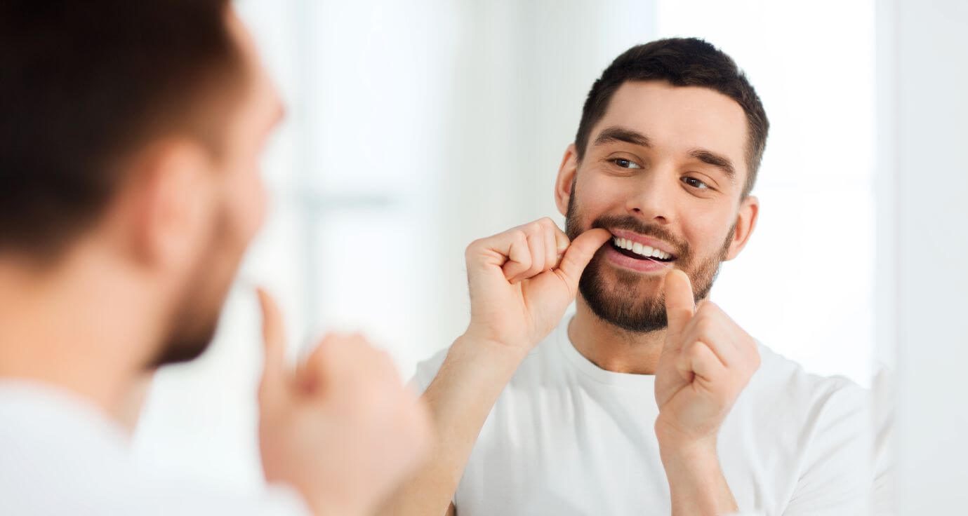 Male stood in mirror applying Invisalign